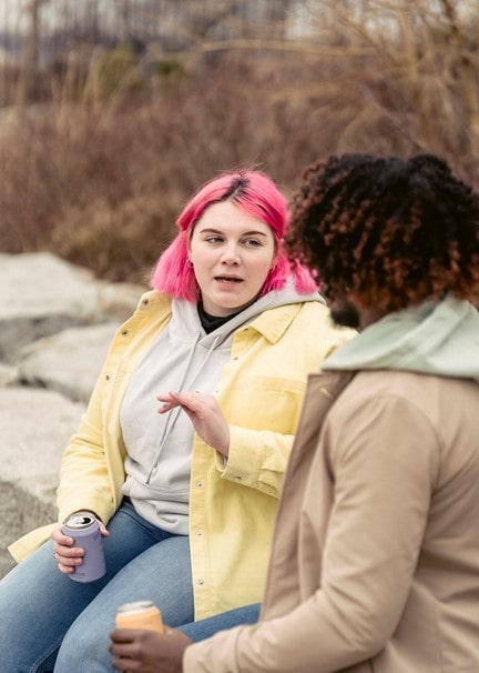 Woman with pink hair speaking to another woman